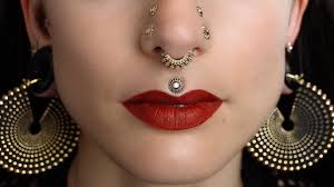 A woman with red lipstick and a silver nose ring.